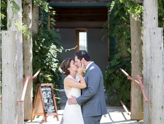 Bride and groom kissing under the wisteria vines, Kelsey Combe